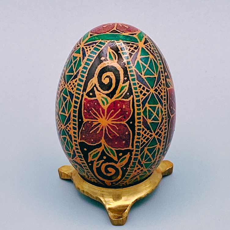 A pysanka (intricately dyed egg) with a pink flower on it.